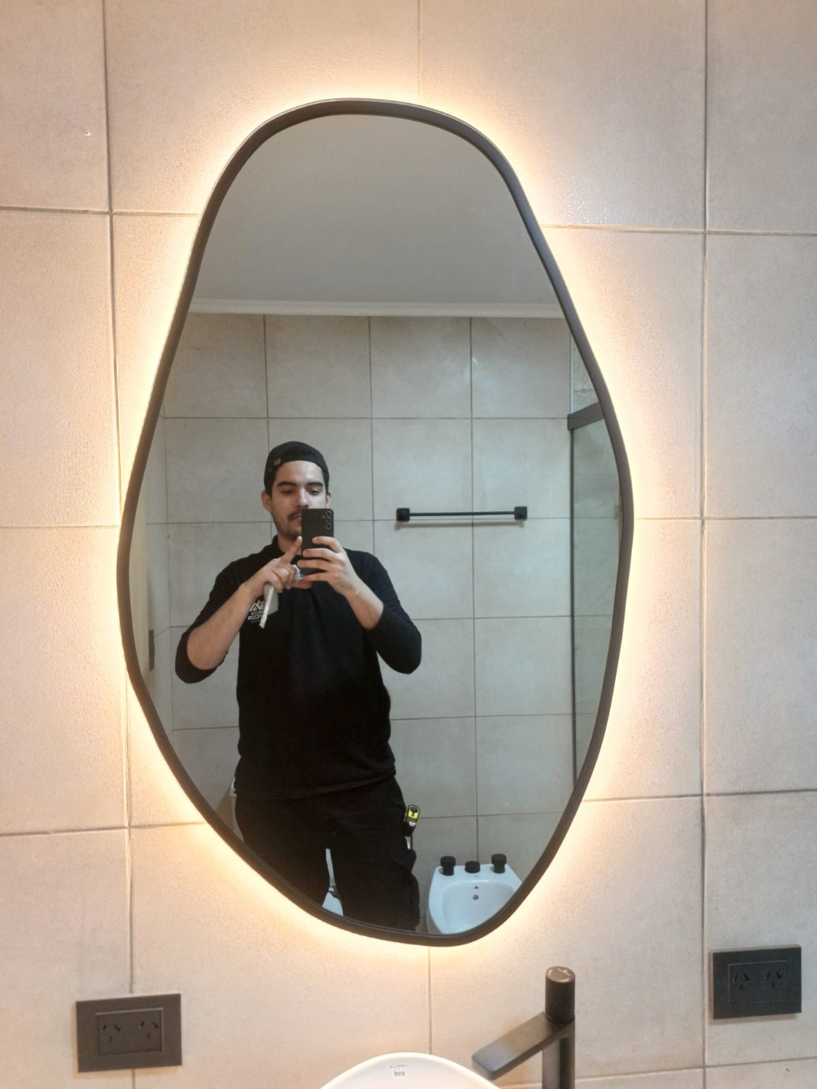 banheiro moderno com espelho irregular iluminado — projeto Solución integral de baño: espejo LED + mampara corrediza — San Justo, por Los Andes Vidrios y Espejos, em Sarratea 4174